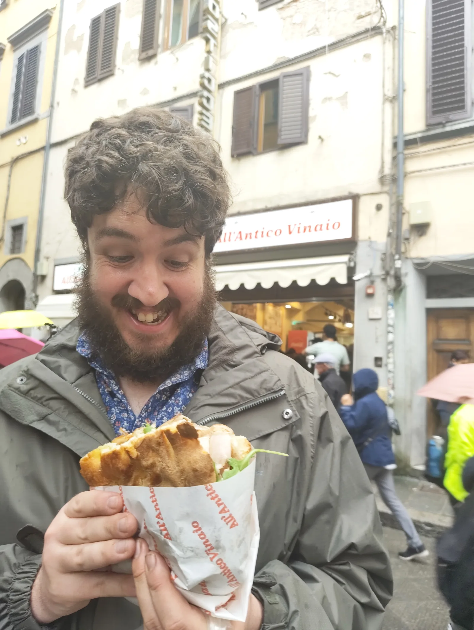 Robert grinning down at a very large sandwich he is holding in both hands.